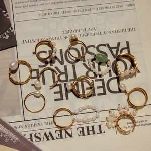 Flat lay of vintage gold rings and earrings with freshwater pearls on newspaper