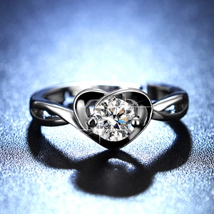 Detail of a heart-shaped moissanite ring with six-prong setting on a deep blue backdrop