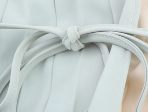 Close-up of the delicate light blue halter tie detail and fine stitching on the pleated dress