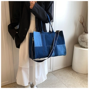 Detail of denim patchwork tote bag with striped shoulder strap and blue colorblock design