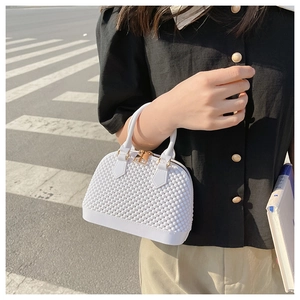 Detail of white shell handbag with unique bubble texture and gold-tone hardware