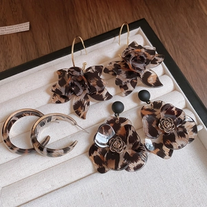 Macro view of leopard print resin flower earrings and C-shape hoops on jewelry tray