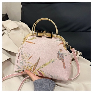 Detail of pink embroidered handbag featuring traditional bird and bamboo leaf patterns
