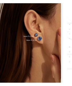 Détail de boucles d'oreilles rondes bleues de 6mm et 8mm sur l'oreille d'un modèle