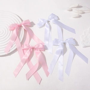 Close-up of pink and white double-layer satin ribbon bow hair clips on elegant tray
