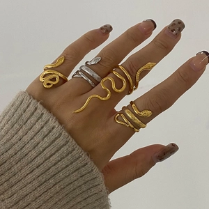 Detailed view of trendy gold and silver snake rings on hand with sleek metallic texture