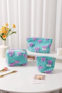 Three-piece plush makeup bag set with purple bow details and soft blue fuzzy texture