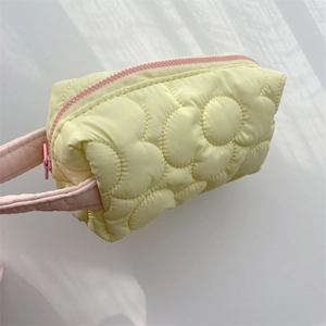 Detailed close-up of yellow quilted polyester cosmetic bag with floral stitching patterns