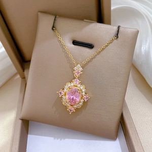 Macro shot of luxury gold necklace with pink oval gemstone and surrounding zircons in gift box