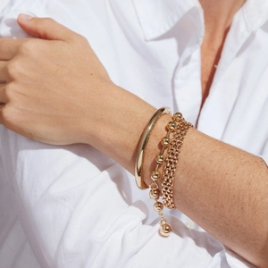 Vue rapprochée de l'ensemble de bracelets en laiton doré poli porté avec style par un mannequin