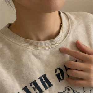 Close-up of minimalist ultra-thin gold water wave chain necklace worn on neck