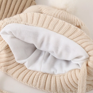 Detail van de dikke warme voering en beige gebreide textuur van de wintermuts voor baby's
