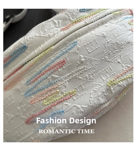 Close-up of white embossed fabric bag with colorful wavy embroidery and zipper detail
