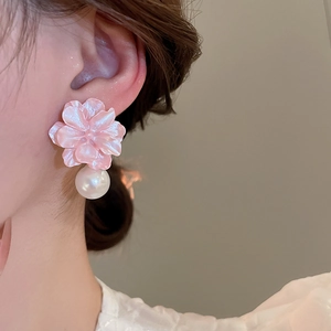 Close-up of a model wearing a pink resin flower earring with a white pearl drop pendant
