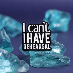 Cartoon enamel pin with 'i can't, I HAVE REHEARSAL' text on blue glass stone