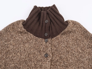 Detail of high rib turtleneck and button closure on brown chunky knit cardigan