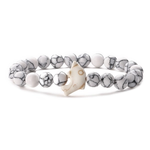 Close-up of dolphin-shaped bead and textured white stone beads on a stretch bracelet