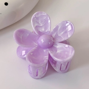 Vue rapprochée de la pince à cheveux fleur mauve avec texture marbrée blanche