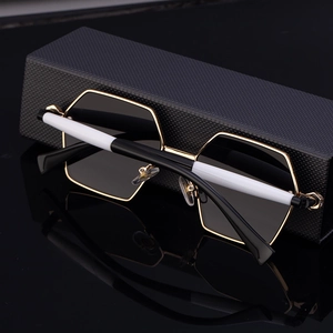 Detail of polygonal sunglasses with black-gold frames and black-white patterned temples