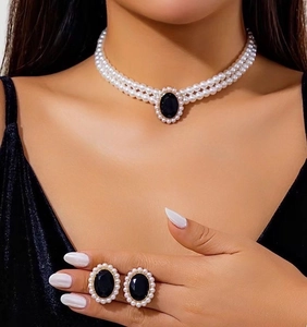 Close-up of triple-layer pearl necklace and earrings with black oval pendant on model