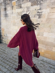 Outdoor shot of wine red oversized cable knit sweater paired with patent leather boots