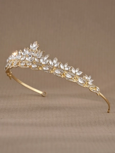 Macro shot of gold bridal crown with crystal rhinestones on a beige textured surface