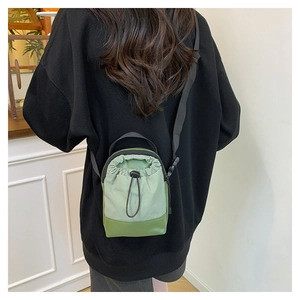 Rear view of model wearing a green drawstring crossbody mini bag with black strap
