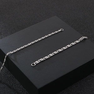 Macro detail of silver stainless steel square pearl link chain with hollow engraved design