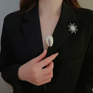 Polished silver sunflower brooch and oval pin set on black formal suit jacket