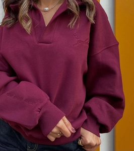 Détail d'un sweat polo bordeaux avec broderie dorée et coupe décontractée oversize