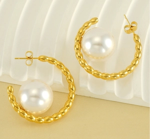Detail of textured gold hoop earring featuring a large round pearl and stud fastener