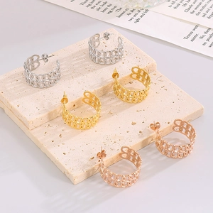 Three-color hollow chain link C-shaped earrings in gold, silver, and rose gold on a stone