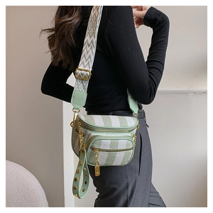 Detail of light green multi-zipper crossbody bag with textured wide woven strap and gold studs
