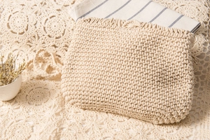 Nahaufnahme der cremefarbenen Web-Clutch mit handgefertigter Baumwollstruktur auf Spitze