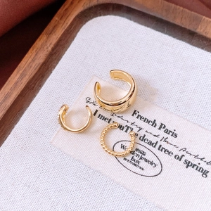 Close-up of three minimalist 18k gold plated ear cuffs on a vintage fabric background