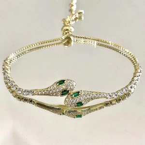 Detail of gold snake bracelet featuring emerald green eyes and sparkling zircon pavé