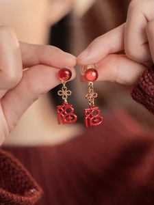Détail de boucles d'oreilles rouges signe Fu avec nœuds chinois dorés et résine