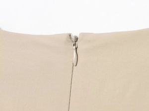 Close-up of seamless invisible zipper detail on beige woven midi dress with cutout