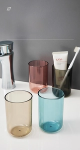 Detail of four transparent plastic mouthwash cups in amber, blue, grey and pink colors