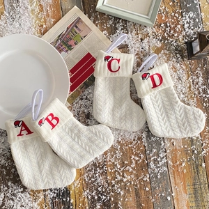 Set of four white cable knit Christmas stockings with red embroidered letters A-D on snow