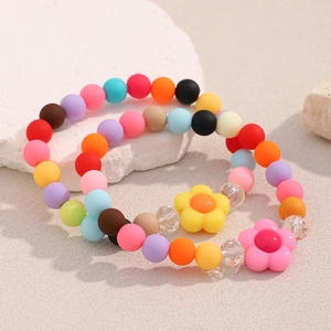 Detail of colorful matte acrylic beaded bracelets featuring candy-colored flower pendants