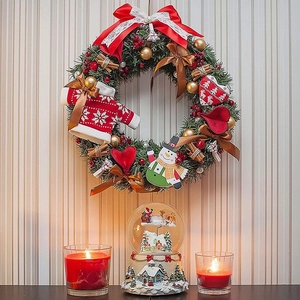Detailed Christmas wreath with pine needles, berries, and ornaments on a striped wall