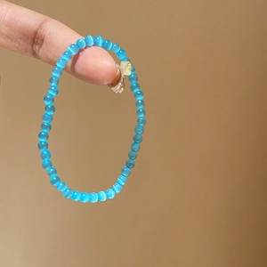 Detailed close-up of blue cat eye stone beads and gold flower charm on beaded bracelet
