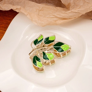 Detailed view of green enamel leaf design on golden alloy hair claw clip