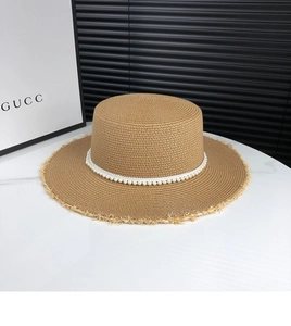 Detail of flat-top straw boater hat with pearl beads trim on marble surface