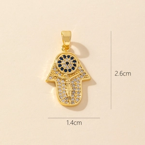 Detail view of gold Hamsa pendant with blue rhinestones and dimensions 1.4cm by 2.6cm