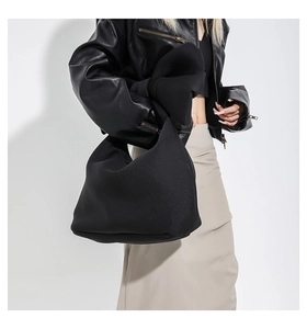 Close-up of minimalist black oversized tote bag worn with a stylish leather jacket