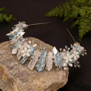 Detailed close-up of handmade crown with pink crystals, blue gems and white pearls