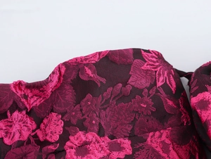 Detailed macro view of dark red jacquard fabric with pink floral texture and subtle gloss