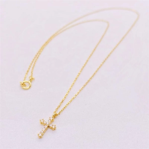 Detailed close-up of golden S925 silver cross pendant with sparkling zircon stones